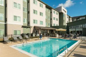 a pool at a hotel with chairs and a building at Residence Inn Pearland in Pearland