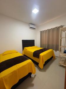 two beds in a room with yellow blankets at CASA COM PISCINA ATE 16 PESSOAS 700mts da praia do aracagy in São Luís