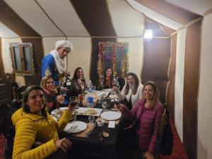 a group of people sitting around a table in a restaurant at Merzouga delicioso Camp in Oulad Akkou