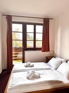 a bedroom with a large white bed with a window at Sport hotel POMI in Harrachov +23 photos