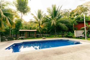 a swimming pool in front of a house with palm trees at Hotel Castillo Blanco in El Zonte