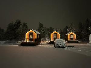 a couple of cottages with a car parked in the snow at Arctic circle cabin 2 in Rovaniemi