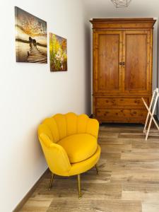 a yellow chair in a room with a cabinet at Il Grande Cipresso B&B in Castelnuovo