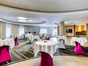 a banquet hall with white tables and pink chairs at Pullman Brussels Centre Midi in Brussels