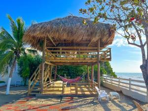 Casa San Miguel Frente al Mar في San Silvestre: كوخ على الشاطئ مع أرجوحة والمحيط