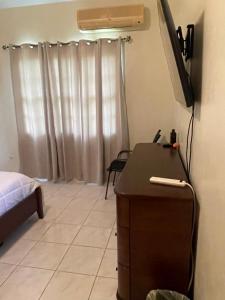 a bedroom with a bed and a dresser and a television at A taste of M&M in Belize City