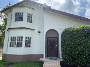 a white house with a door and a bush at A taste of M&M in Belize City