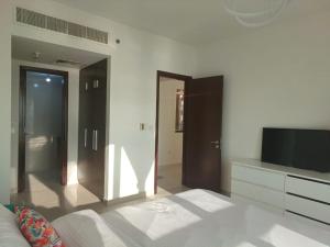 Panoramic B8 Sea View two bedroom apartment في أبوظبي: غرفة معيشة مع تلفزيون وأريكة