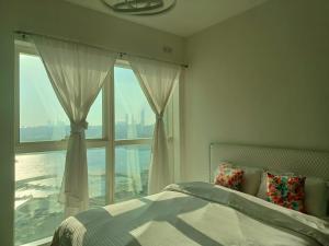 Panoramic B8 Sea View two bedroom apartment في أبوظبي: غرفة نوم بها سرير ونافذة كبيرة