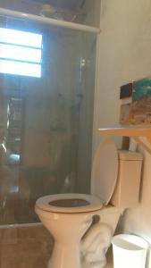 a bathroom with a toilet and a glass shower at Quarto do Sol Relaxante - 150m da praia in Ubatuba