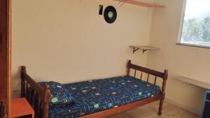 a small bed in a room with a clock on the wall at Quarto do Sol Relaxante - 150m da praia in Ubatuba