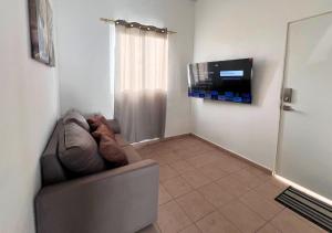 un salon avec un canapé et une télévision à écran plat dans l'établissement Colibri de Montaña, à Ahuachapán