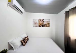 Cette chambre blanche dispose d'un lit et de deux photos sur le mur. dans l'établissement Colibri de Montaña, à Ahuachapán 13 autres photos