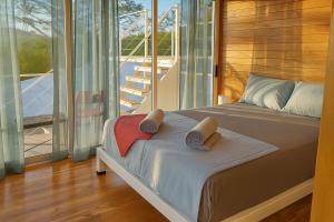 a bedroom with a bed and a balcony with sliding glass doors at luxury wooden house mountain view in Hojancha +8 photos