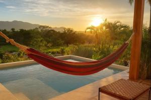 a hammock is hanging over a swimming pool at luxury wooden house mountain view in Hojancha