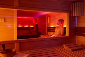 a man sitting in a sauna with a mirror at Göbel's Hotel AquaVita in Bad Wildungen