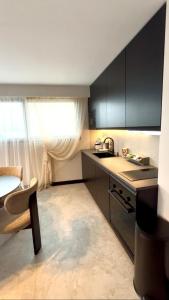 a kitchen with black cabinets and a sink and a table at Appartement cosy proche de la Croisette et du Palais des Festivals in Cannes