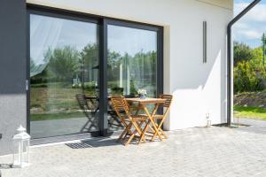 a patio with a table and chairs in front of windows at Luksusowy Apartament Pod Lasem Szczecin-Pilchowo EV Stacja ładowania in Pilchowo +1 photo