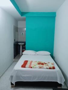 a bedroom with a bed with a blue wall at Casa Hotel El Eden in Carepa