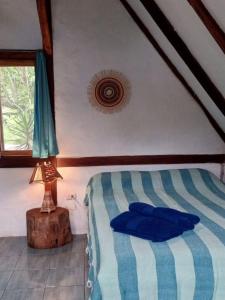 a bedroom with a bed and a lamp and a window at Las Cabañas de la Iguana in Ayampe