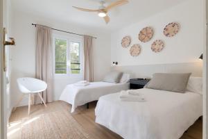 een witte slaapkamer met twee bedden en een raam bij Apartamento Rosari II in Vilassar de Mar