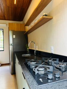a kitchen with a black counter top with a sink at Recanto Gamboa in Garopaba +6 photos