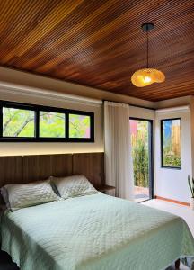 a bedroom with a bed with a wooden ceiling and windows at Recanto Gamboa in Garopaba