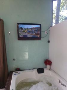a tv hanging on a wall above a bath tub at Residencial Rodrigues Florianópolis in Florianópolis