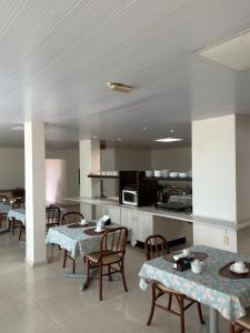 a room with tables and chairs and a kitchen at Hotel Boa Vista - 200mts do Shopping Pátio in Chapecó +20 photos