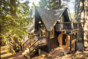 a tree house with a staircase in the woods at Lightfoot Cabin Mid-Century Perfect Romantic Getaway Hot Tub Sauna in Running Springs