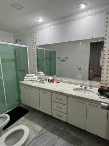 une salle de bain avec deux lavabos et un WC et un miroir dans l'établissement Flat no coração de Alphaville, à Barueri 10 autres photos