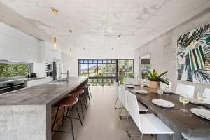 Una cocina grande con una barra larga con sillas blancas. en The Opal at Coolum - Mountain and Ocean Views, en Yaroomba