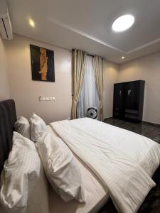 a bedroom with a large bed with white sheets at The Dream Residence in Abuja