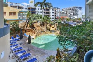 a swimming pool with chairs and a water slide at Landmark 1 Bedroom Beachside Escape in Mooloolaba