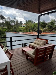 a deck with a bench and a table and chairs at Casa Moderna en el Bosque Jacuzzi y Deck Privado in Mazo