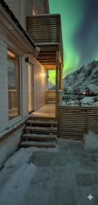 a house with a porch with a green northern lights at Aurora Bay Villa Lofoten in Sund