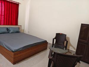 a bedroom with a bed and a chair and a table at JM Niwas in Guwahati