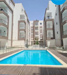 a swimming pool in front of two apartment buildings at Apartment222 2 rooms Al Bousten Hammamet in Hammamet Sud