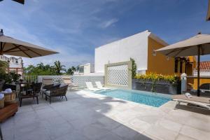 a backyard with a swimming pool and an umbrella at Hotel Casa del Gobernador in Cartagena de Indias