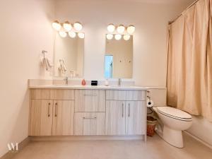 a bathroom with a toilet and a sink and a mirror at Oso Skyview Suite - DT modern 2 bed, 2 bath in Golden +24 photos