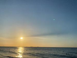 a sunset over the ocean with people in the water at Villa vacacional piscina en playa dormida in Santa Marta