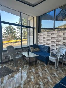 a living room with a couch and chairs and windows at Askari Lodges Murree in Murree