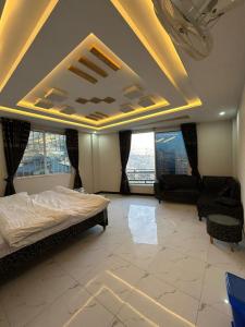 a bedroom with a bed and two chairs and windows at Askari Lodges Murree in Murree