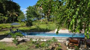 a swimming pool with two benches and an umbrella at Melaya Cabanas in Candikesuma