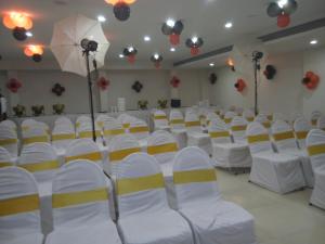 an empty room with white chairs and an umbrella at Veronica Hotel in Vadodara