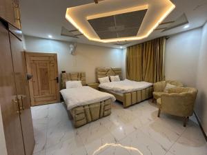 a room with two beds and a chair and a ceiling at Askari Lodges Murree in Murree