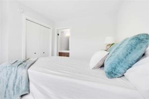 uma cama branca com almofadas azuis em cima em Lakeview at Prairie Pointe em Winnipeg