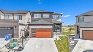 Uma casa grande com uma garagem laranja na entrada de carros. em Lakeview at Prairie Pointe em Winnipeg