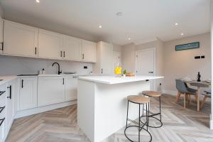 een keuken met witte kasten en een tafel en stoelen bij Modern High Spec Home in Titsey +13 foto's