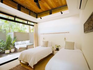 two beds in a room with a window at Nalu Nosara Pool Villa Sombra in Nosara